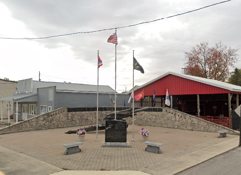 Alger Marion Township Veterans Memorial with flags, stone walls, benches, and a central dedication marker.